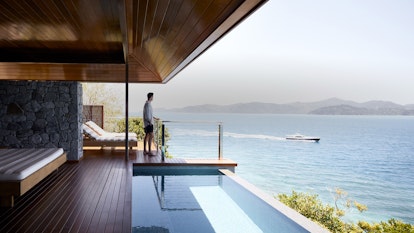 Man on qualia Windward Pavilion private deck with plunge pool looking out to luxury boat within view of the Whitsundays 